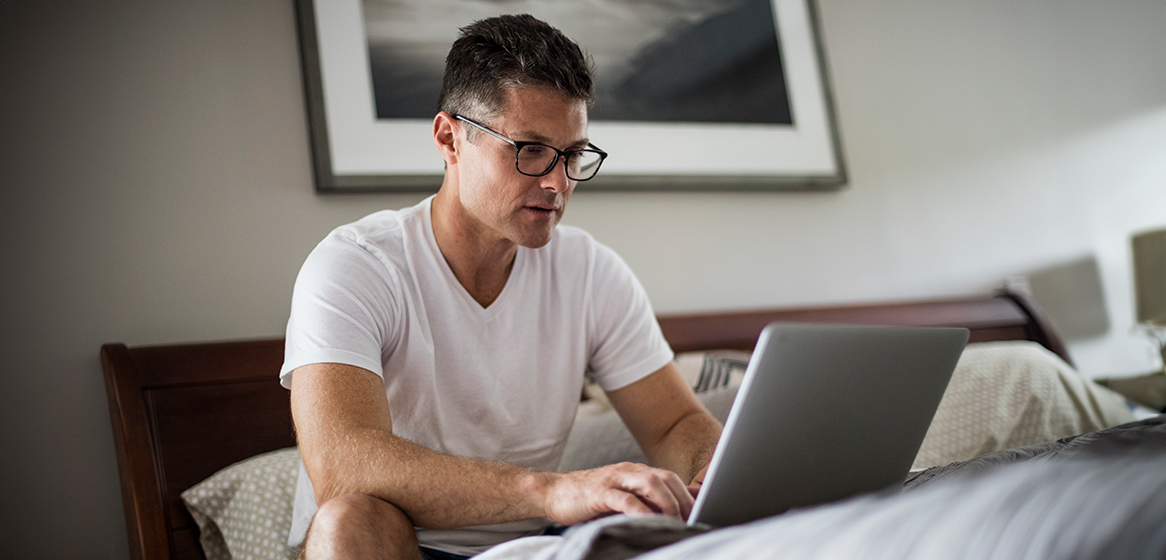man on laptop sitting up in bed